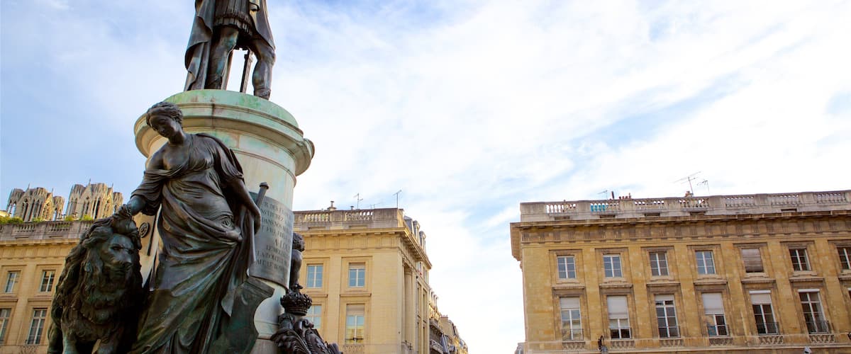 A statue of a woman holding a book and a lion, with a building in the background.