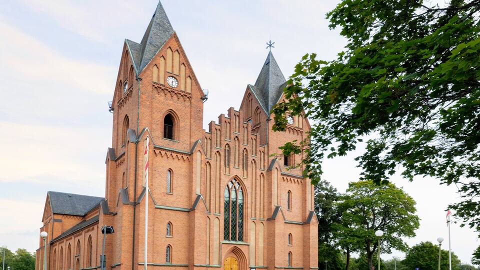 A large brick church with pointed towers and a prominent arched entrance.