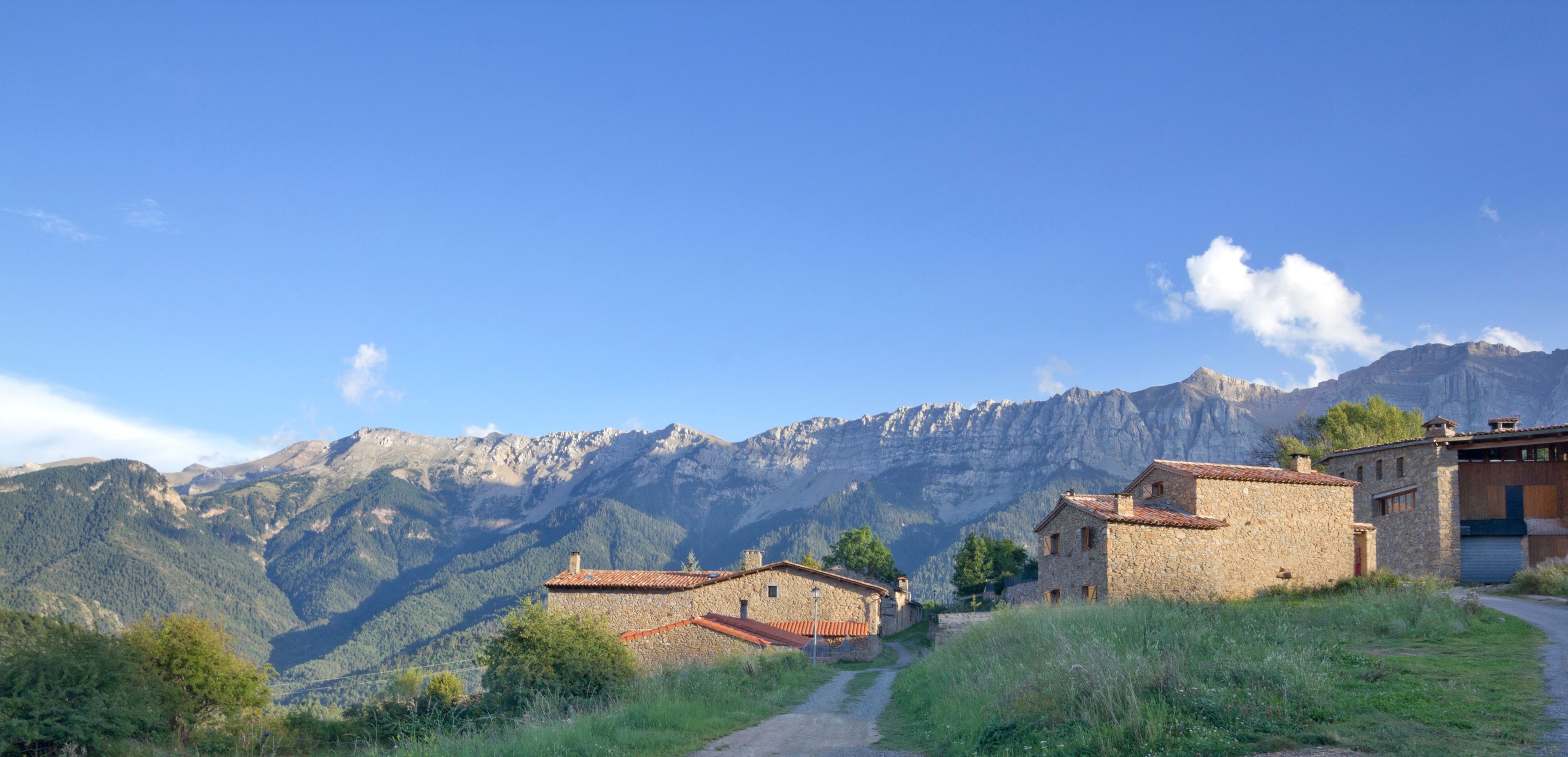 Un village de montagne aux maisons en pierre, sous un ciel d’un bleu limpide.