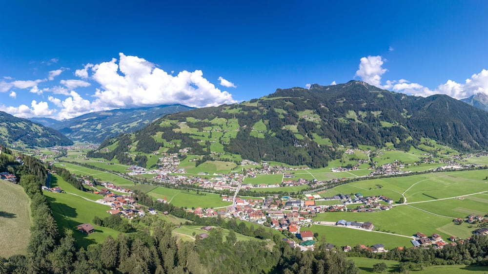 Une vallée où se trouve une petite ville, entourée de montagnes et de champs verdoyants.