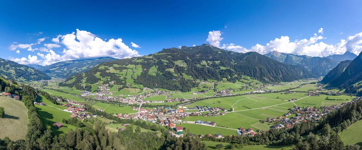 A valley with a small town surrounded by mountains and green fields.