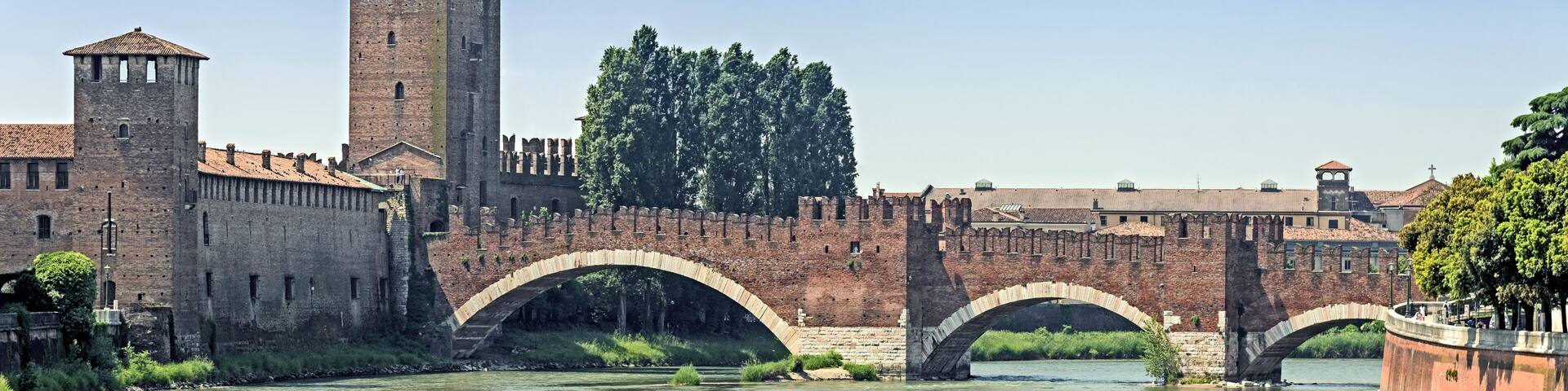 A historic stone bridge over a river, a tall tower, and a fortified wall with arched bridges.
