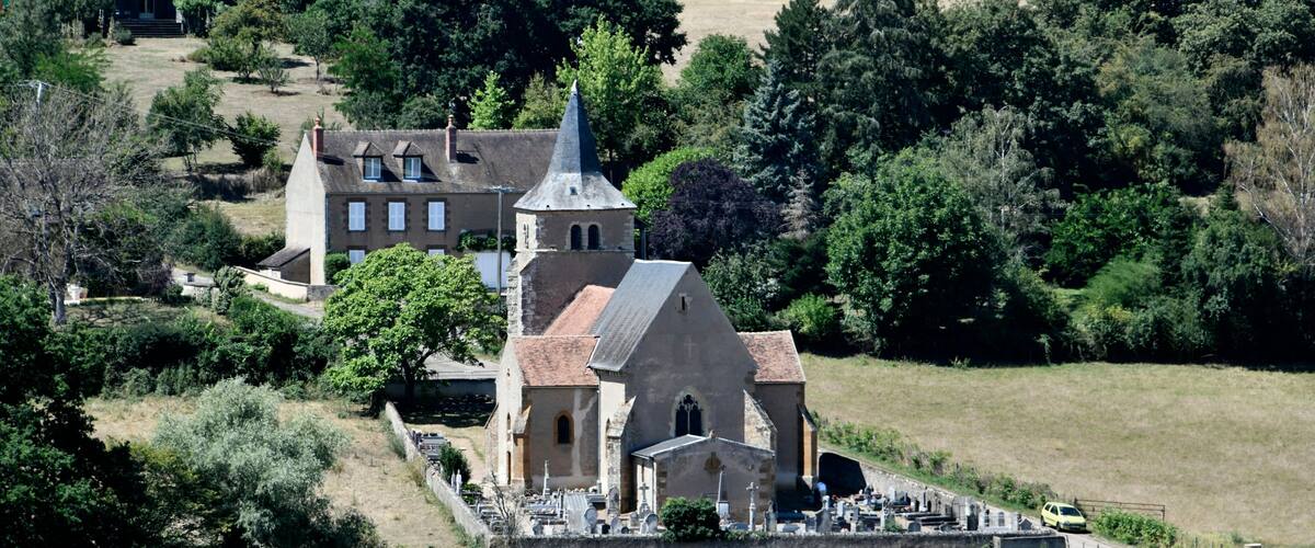 A church surrounded by trees and a cemetery.