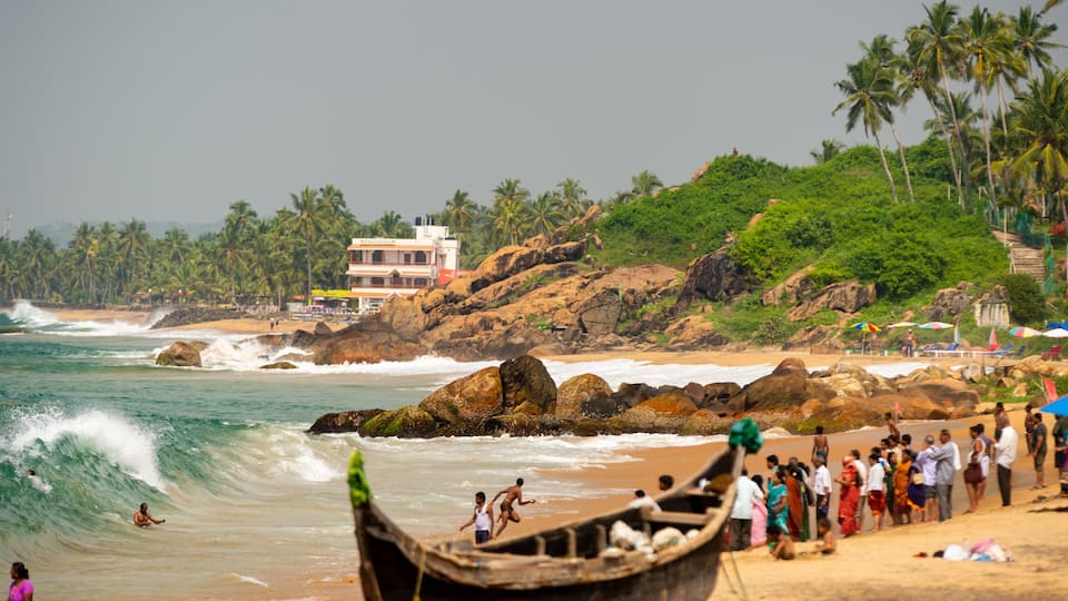 A beach with waves, people, and a boat.