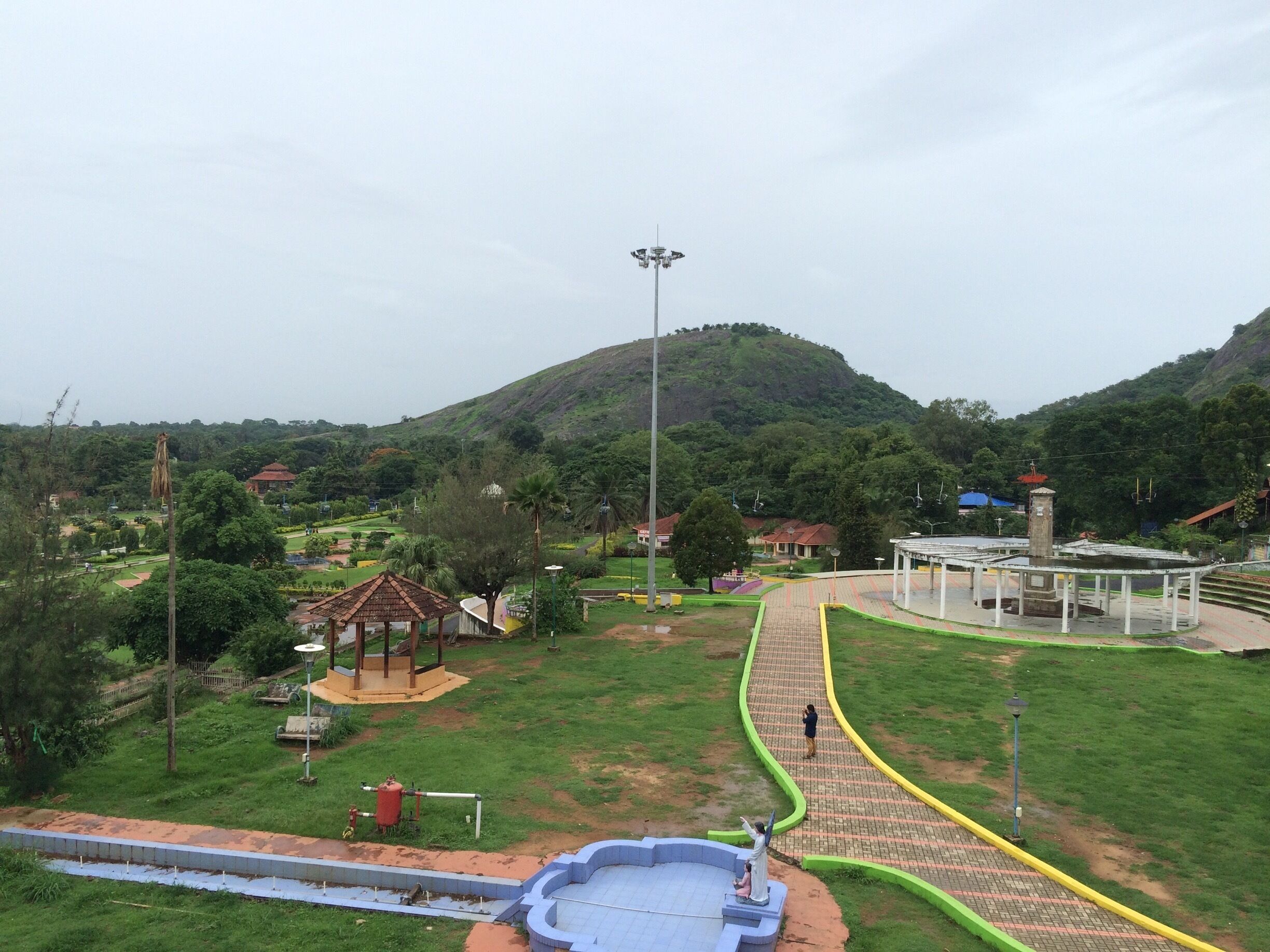 A park with a playground, a gazebo, a fountain, and a hill in the background.