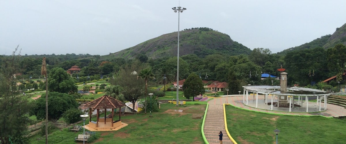 A park with a playground, a gazebo, a fountain, and a hill in the background.