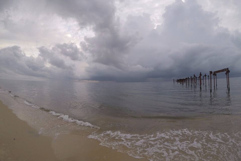 Een strand met golven en een bewolkte lucht.