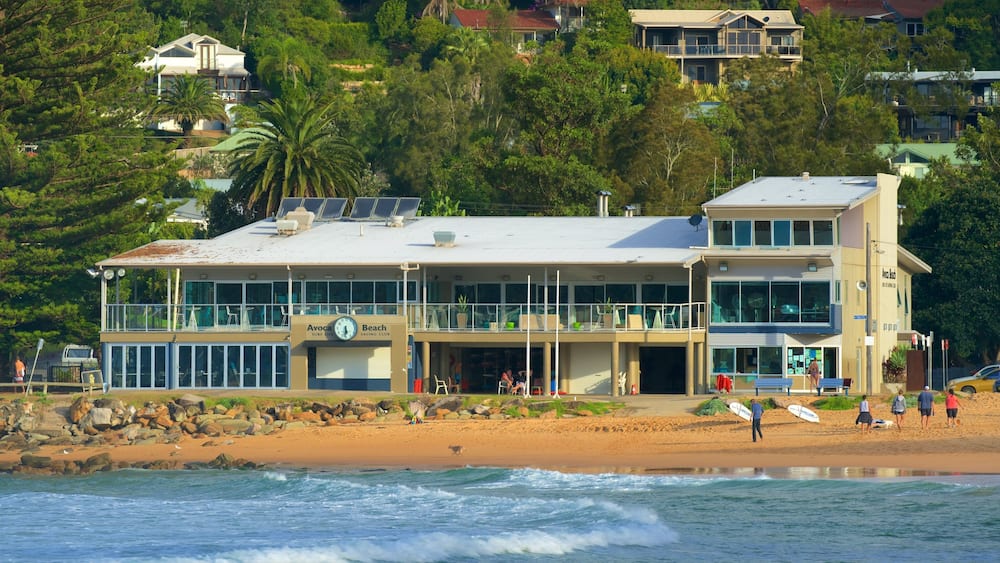 A beachside building with a clock, surrounded by a sandy beach and ocean waves.