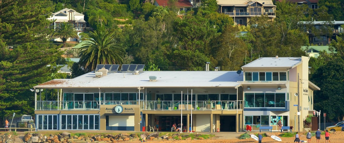 Um edifício à beira-mar com um relógio, rodeado por uma praia de areia e ondas do oceano.