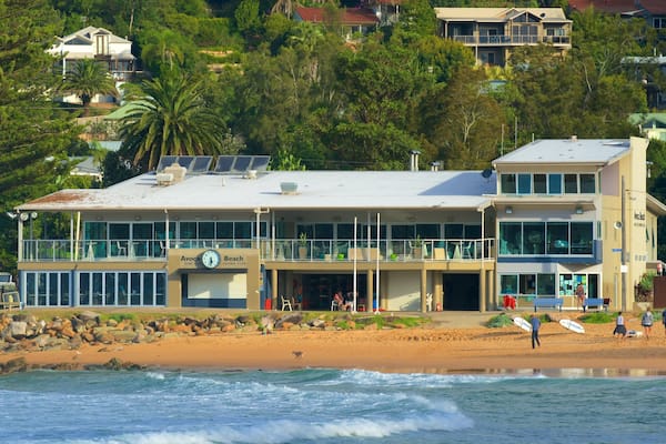 Un bâtiment situé au bord de la plage, doté d’une horloge, entouré d’une plage de sable et des vagues de l’océan.