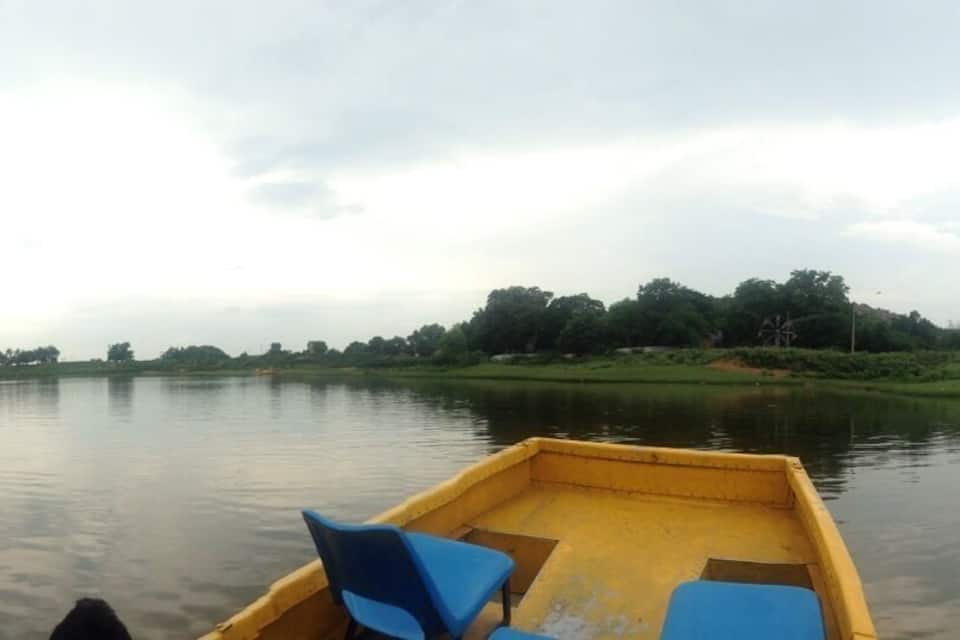 A calm river with a boat in the foreground and a distant tree line on the opposite bank.