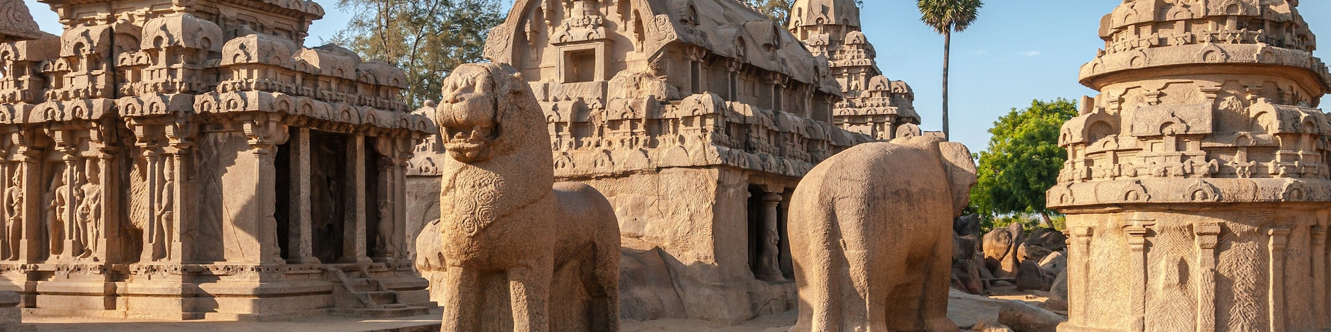 Antiguas tallas y estructuras de piedra, incluyendo una destacada estatua de león y arquitectura de templo intrincada.