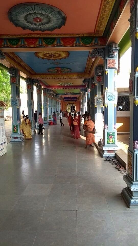 A corridor with ornate columns and a colorful ceiling, lined with people.
