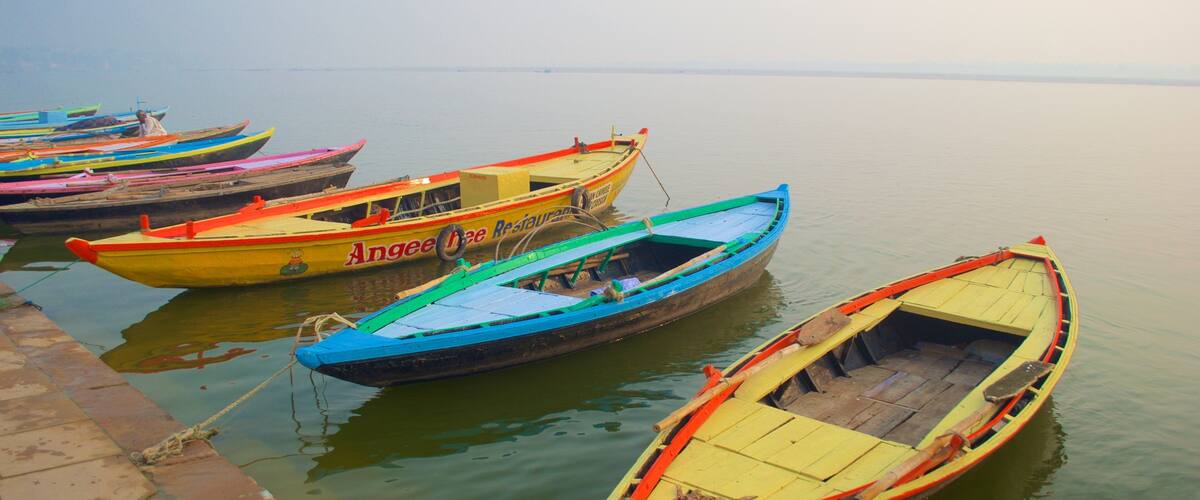 A row of colorful boats docked at a calm body of water.
