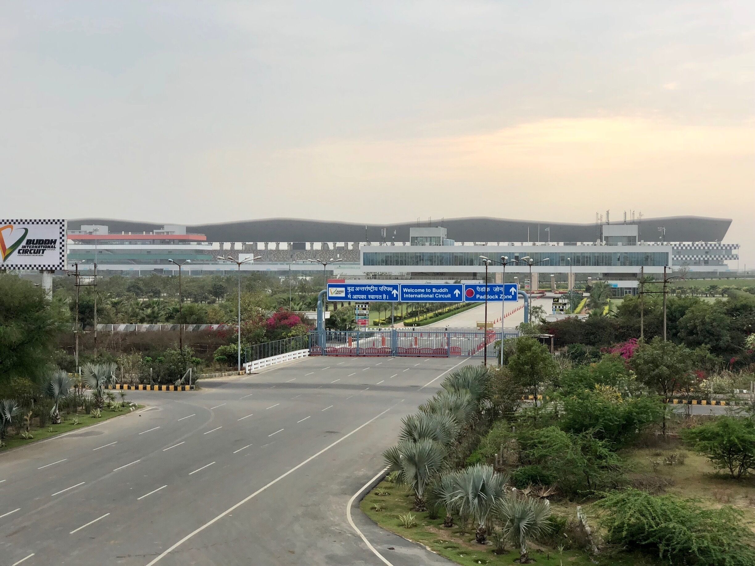 A road leading to an airport with a sign for the Buddha International Circuit.