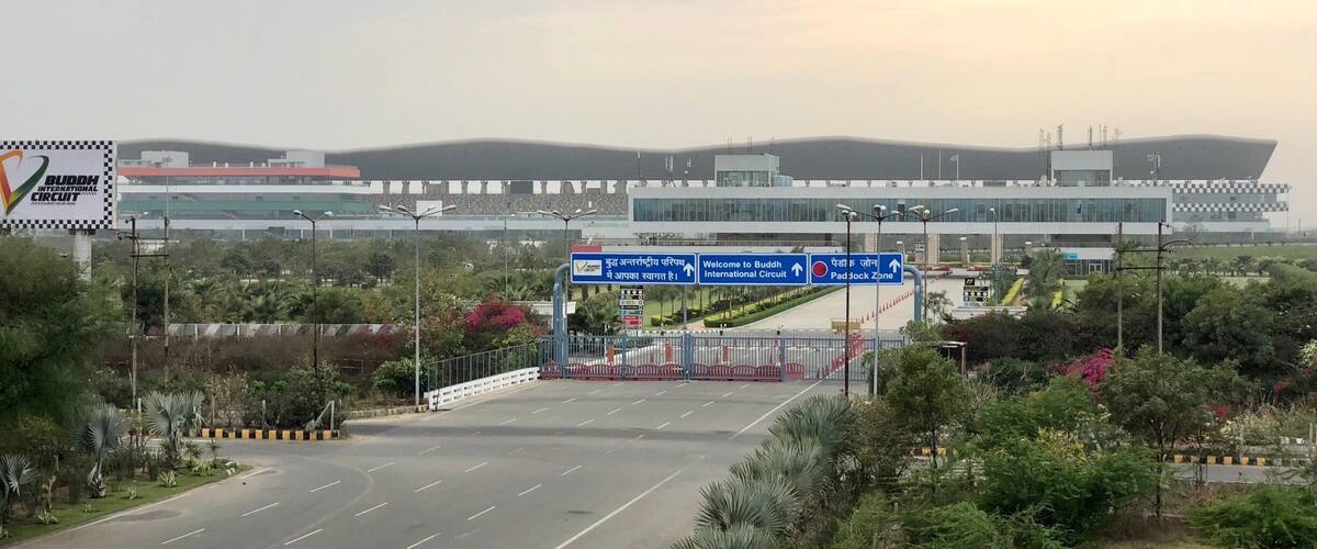 A road leading to an airport with a sign for the Buddha International Circuit.