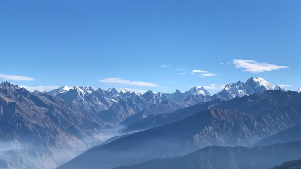 A mountain range with snow-capped peaks under a clear blue sky.