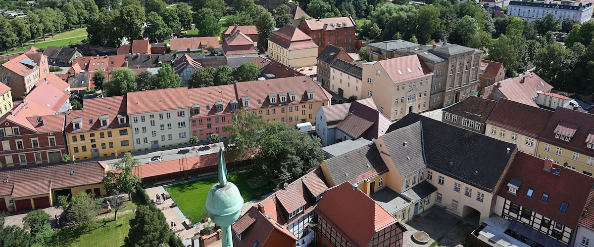 A town with historic buildings, a prominent church tower, and surrounding green fields.