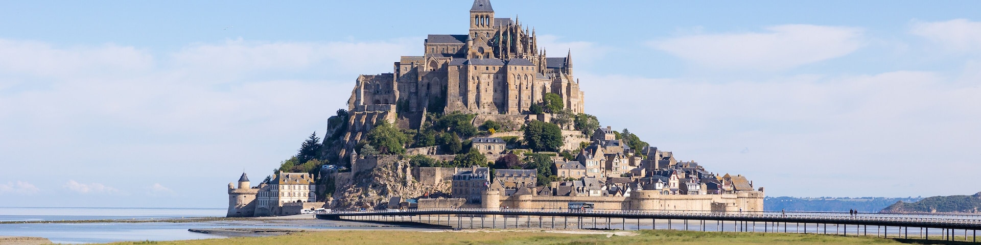 Vue sur le Mont Saint-Michel devant un pâturage des prés salés et ses agneaux