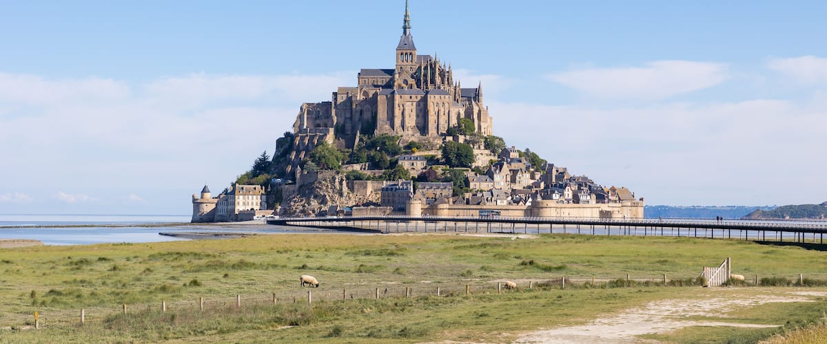 A historic castle on a hill with a bridge leading to it.