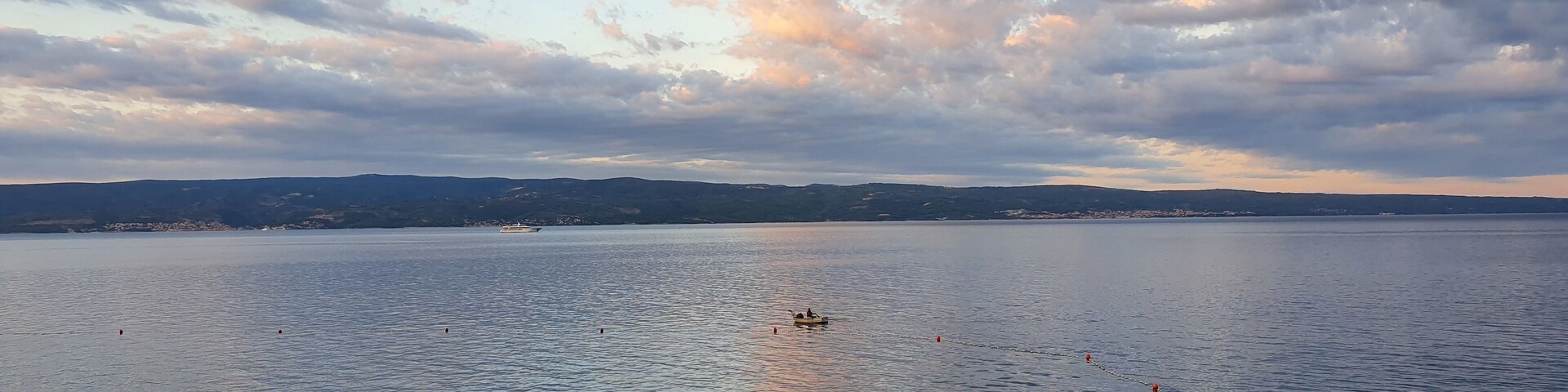 A calm lake with a clear sky and distant hills.
