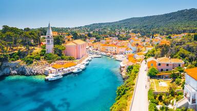A coastal town with a church, a tower, and a marina with boats.