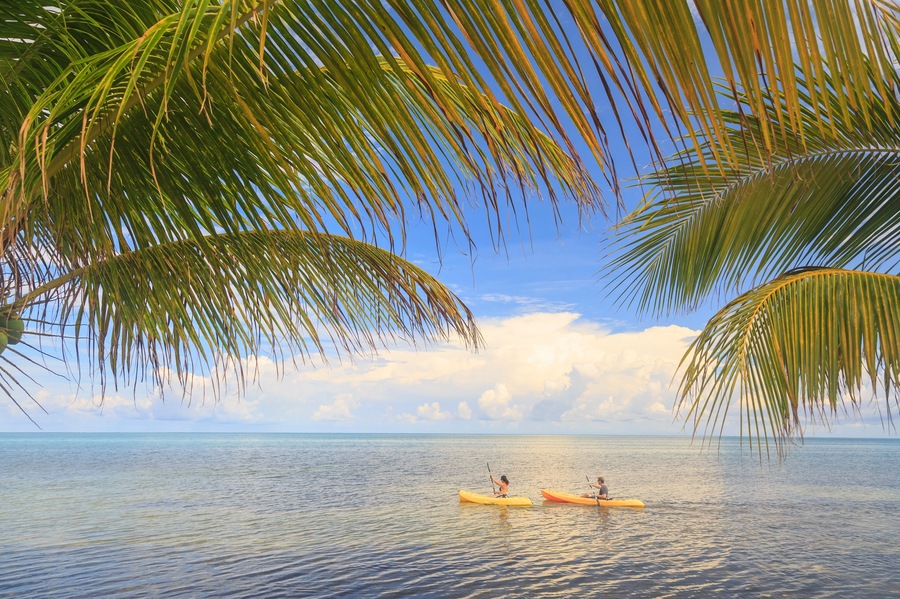 Distant view of couple sea kayaking, St. Georges Caye, Belize, Central America