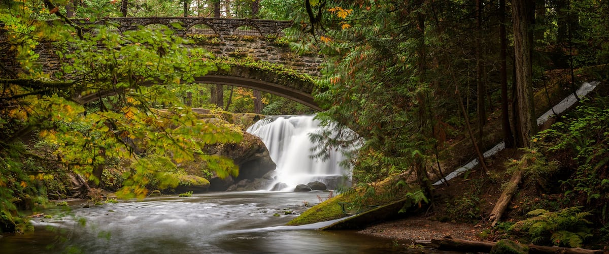 Waterfall in Whatcom Falls Park. A beautiful waterfall runs through this 241-acre park located in a rainforest environment with fir, maple and cedar trees. Autumn has arrived with colorful leaves.