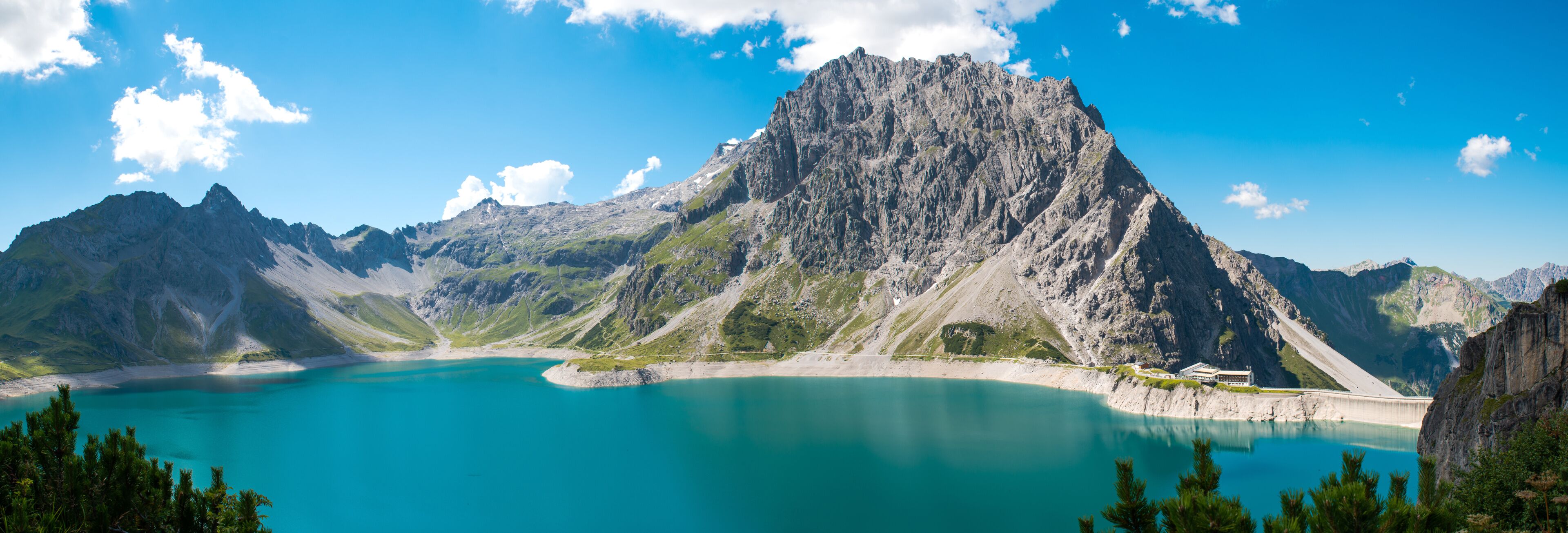 A mountain lake with a prominent peak, clear turquoise water, and surrounding rocky terrain.