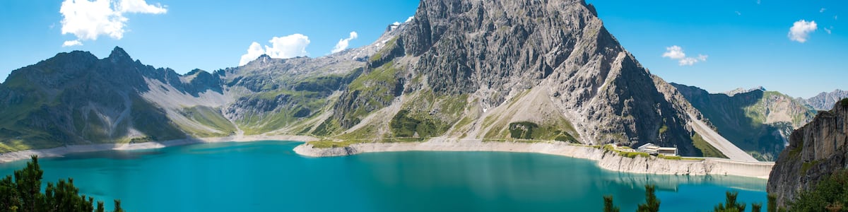 Ein Bergsee mit einem markanten Gipfel, klarem türkisblauem Wasser und umgebendem felsigem Gelände.