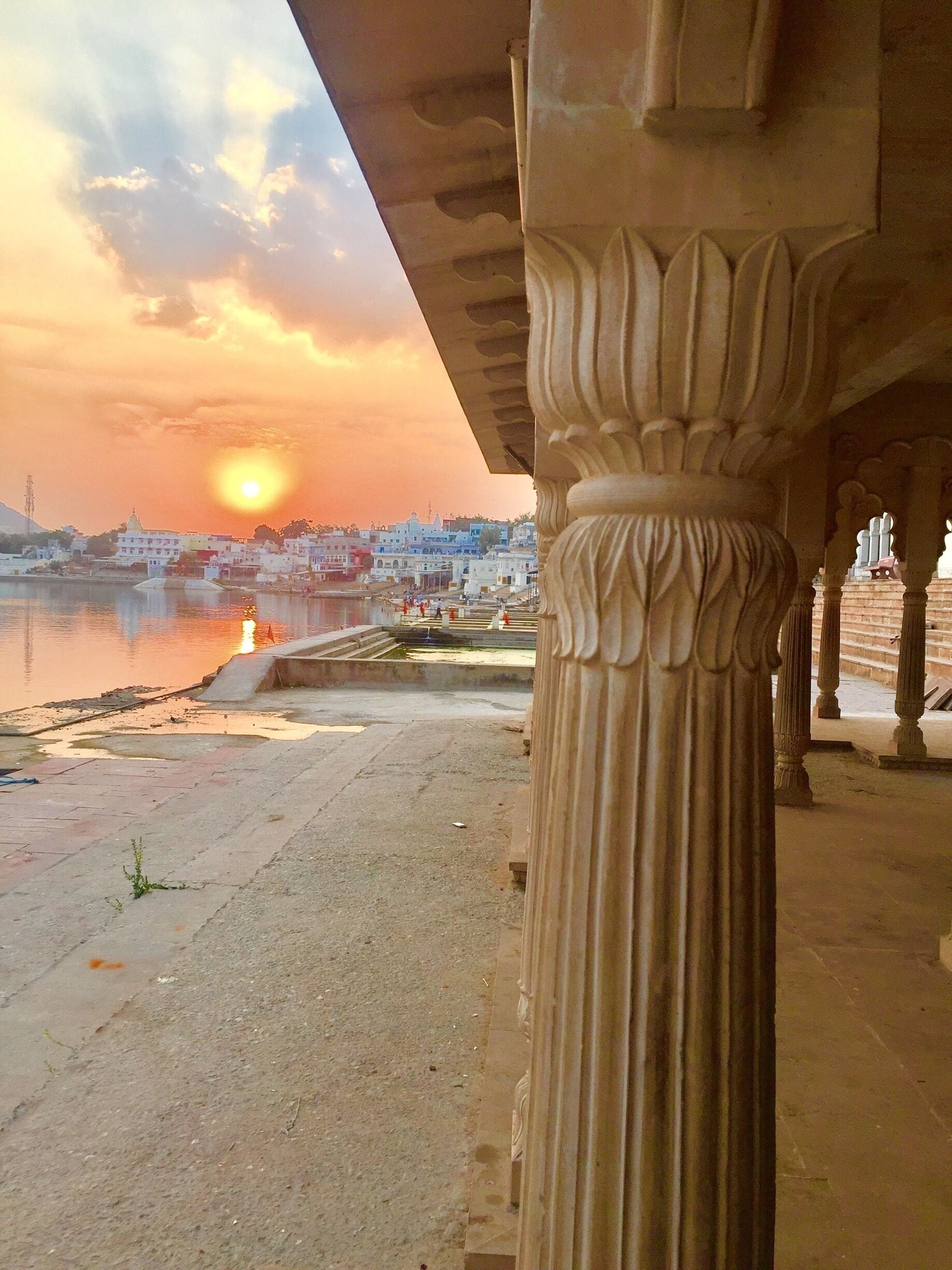 Tramonto su una città con un fiume, caratterizzato da architettura classica e una colonna imponente.