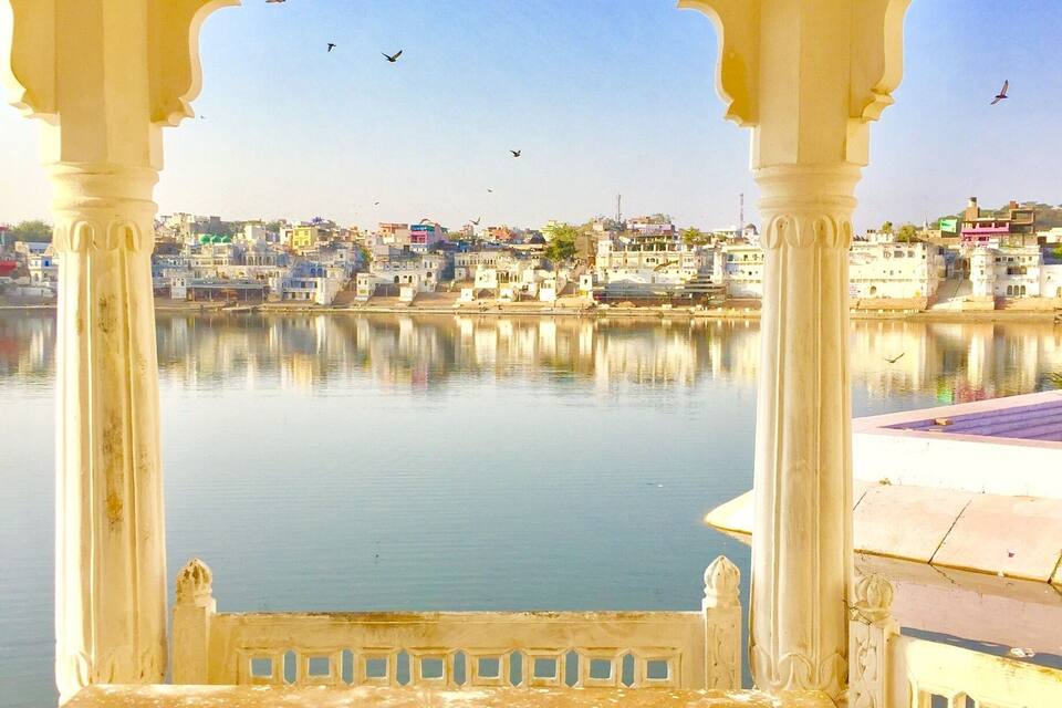 A pavilion with a view of a calm river and a cityscape in the background.