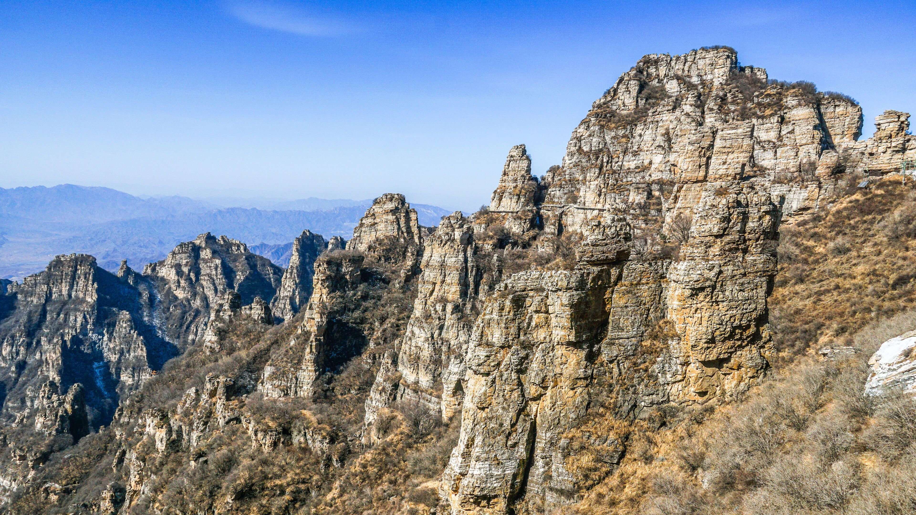 A rugged mountain range with prominent rock formations and sparse vegetation.