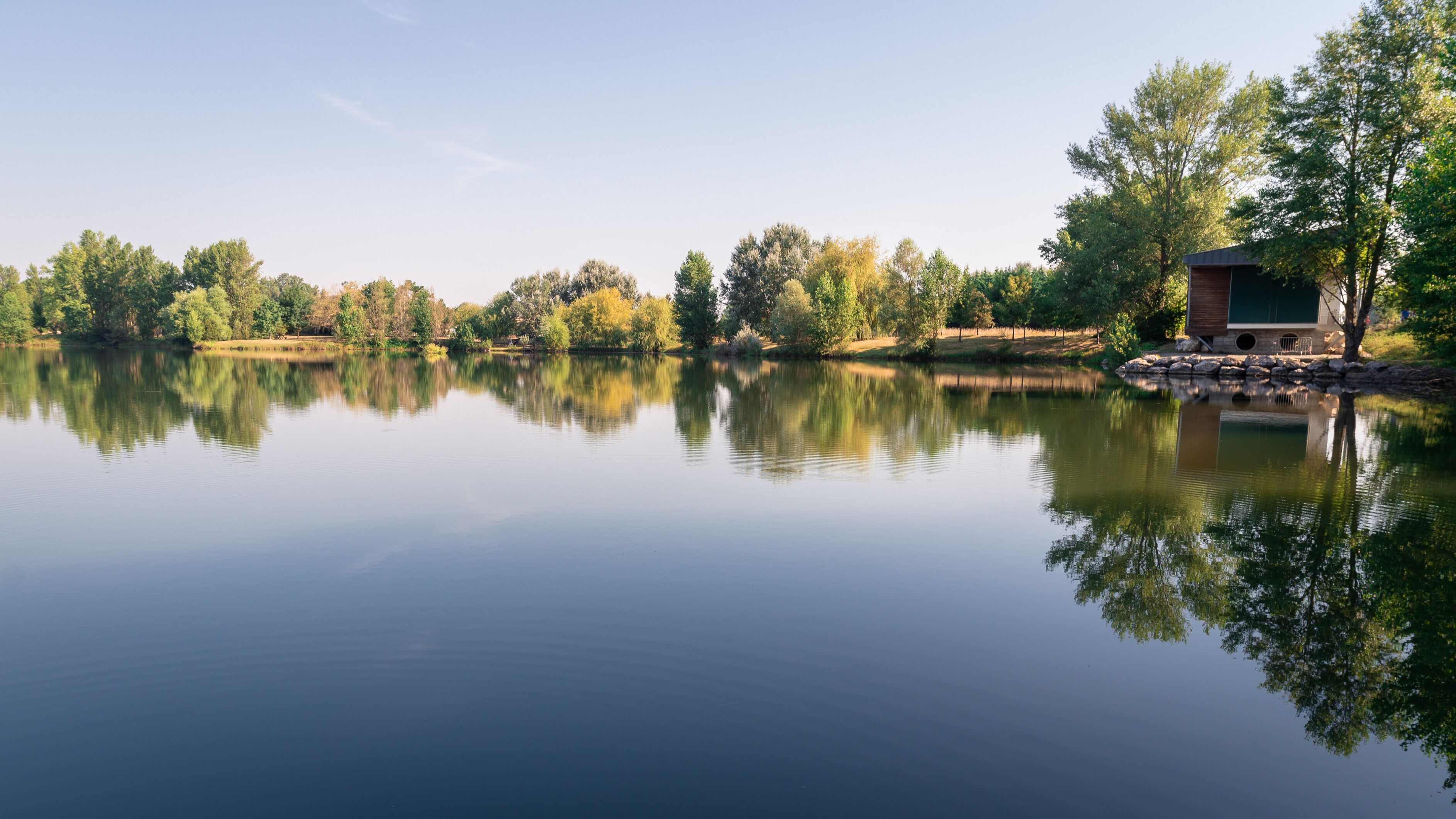Lac de Lamartine, reflet des arbres sur l'eau. Vue sur le lac durant une journée d'été.Roques, Frouzins, France