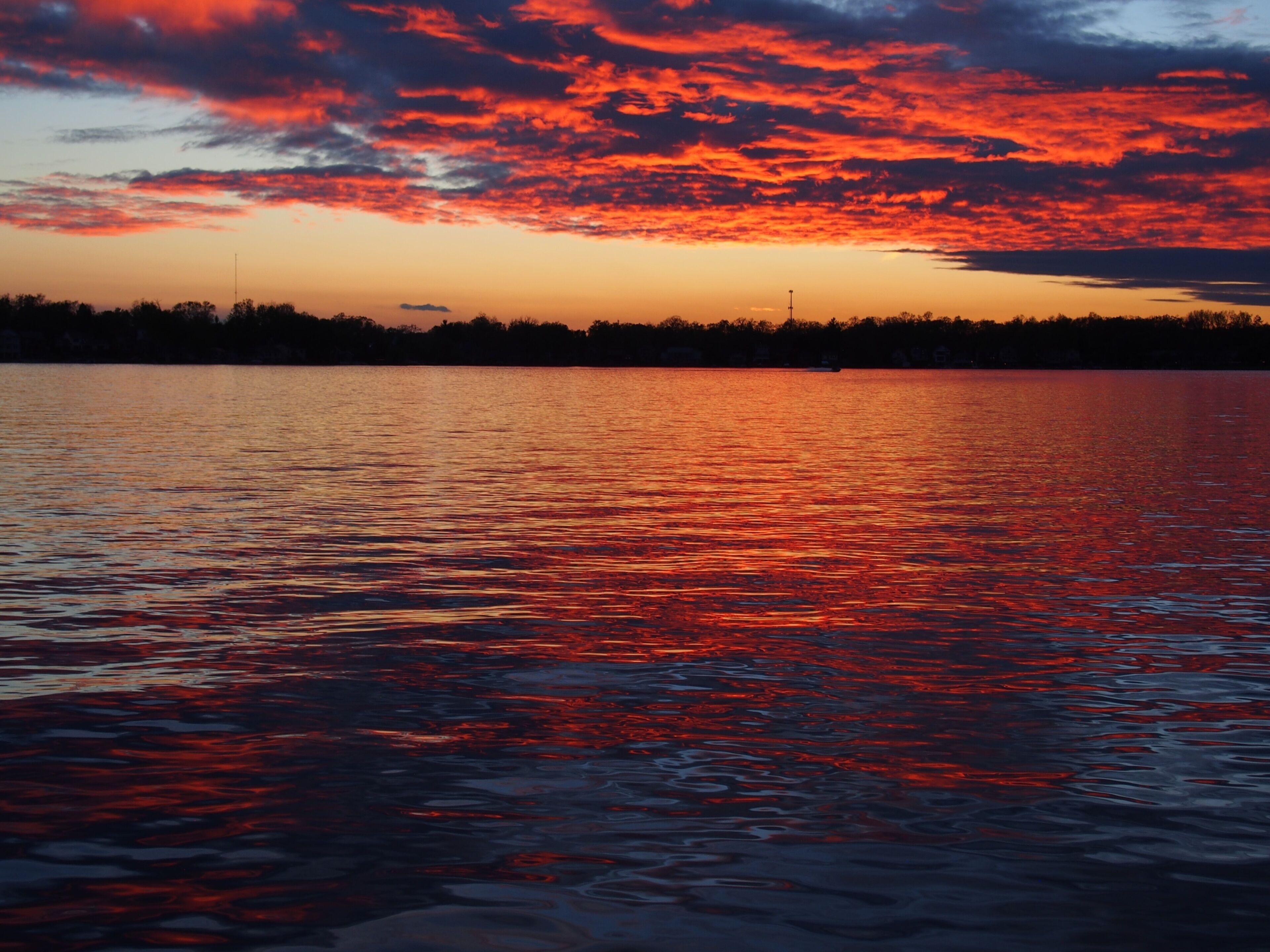 Michigan boaters enjoying a peaceful sunset on Lake Lansing in Haslett, Mi