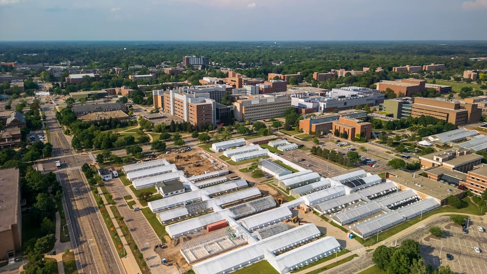 Une vue aérienne d’un campus comprenant plusieurs bâtiments, des espaces verts et un parking.