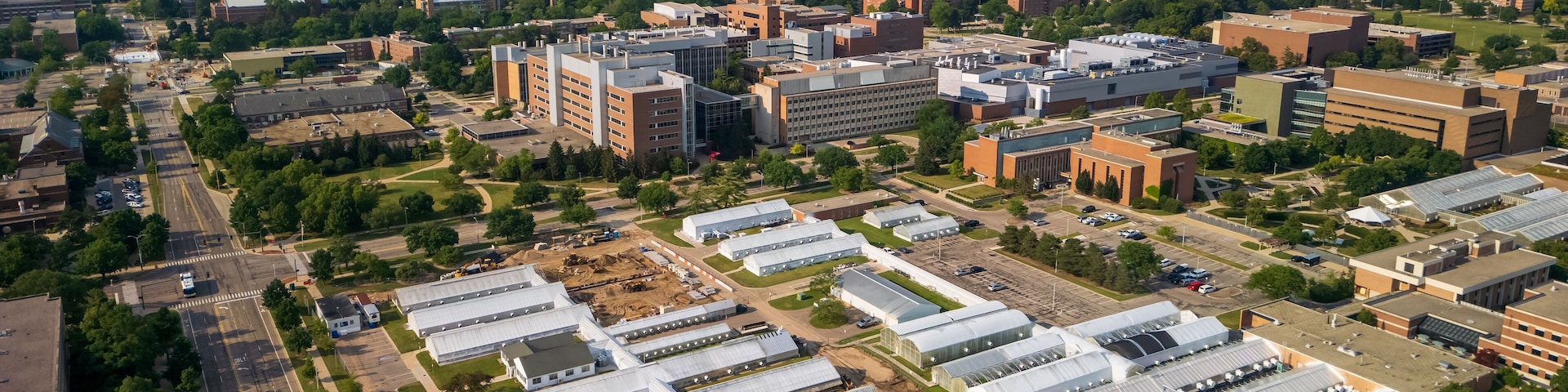 Vista aérea de un campus con varios edificios, zonas verdes y un estacionamiento.