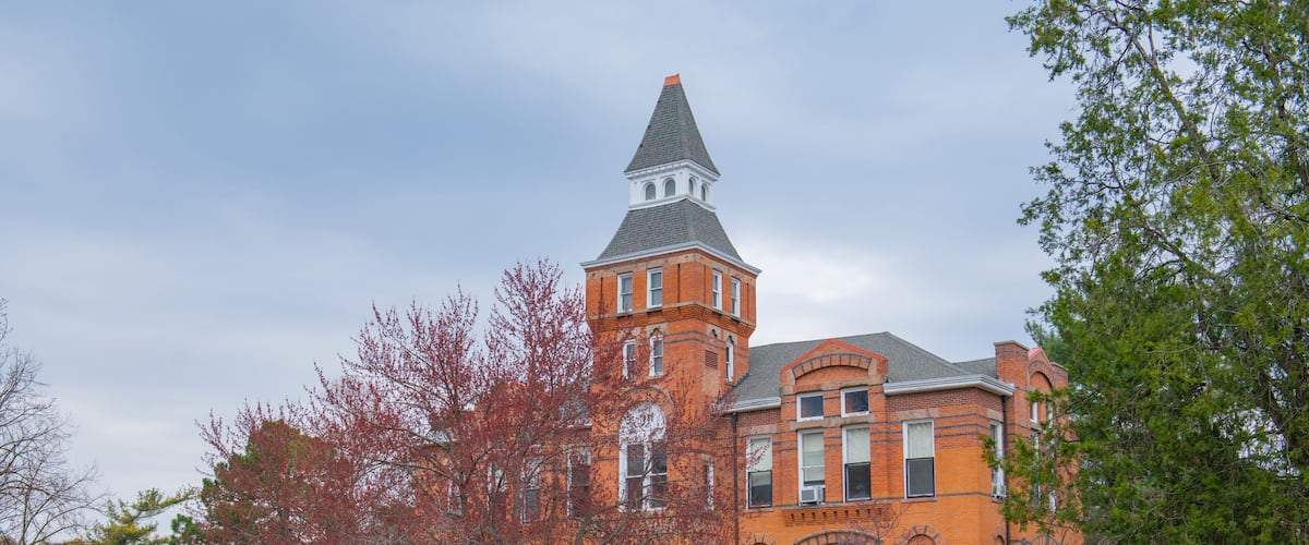 A large brick building with a prominent tower and arched windows.
