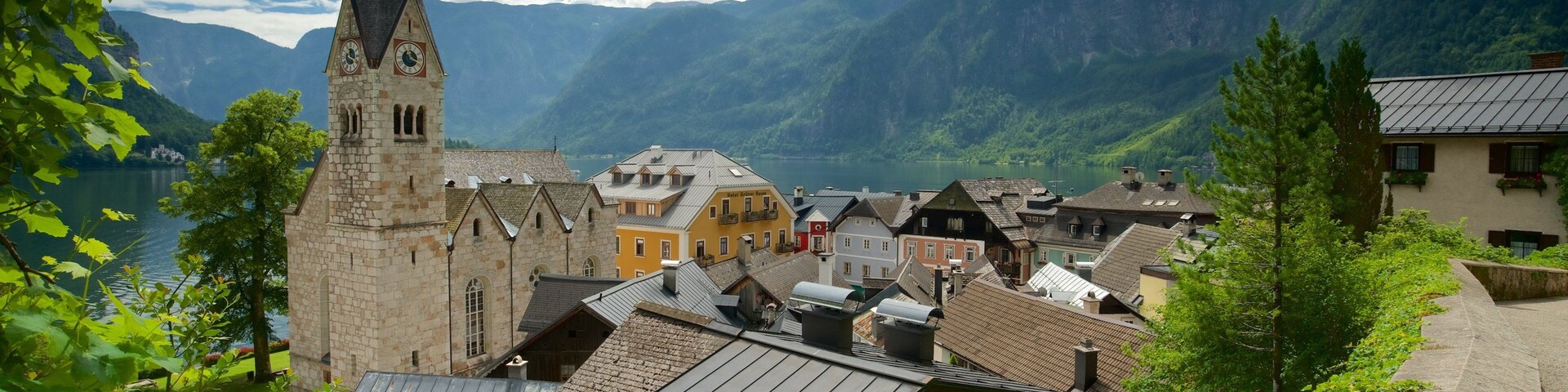 Eine Stadt mit einem markanten Kirchturm, einem See und Bergen im Hintergrund.