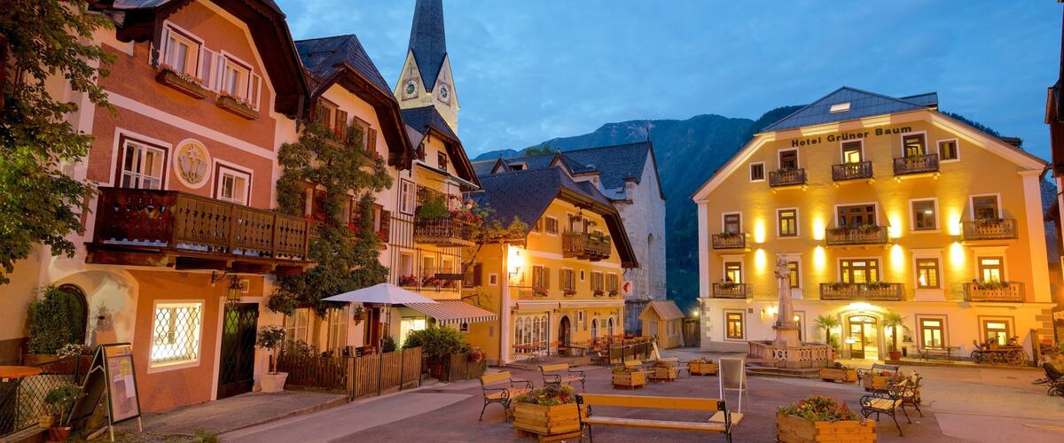 A European village square with traditional buildings, a church spire, and a hotel named 'Hotel Grüner Baum'.