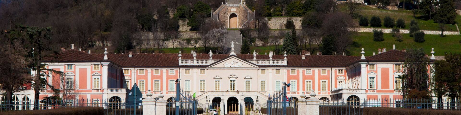 A grand building with a central tower, surrounded by a formal entrance and lush greenery.