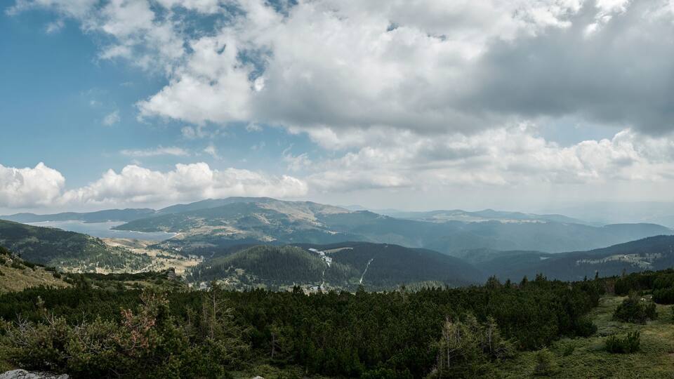 A mountainous landscape with dense forests and a winding river.