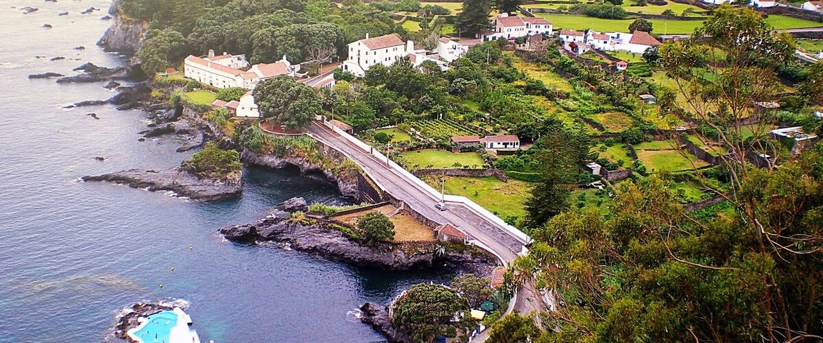 A coastal town with a bridge, rocky coastline, and a swimming pool.