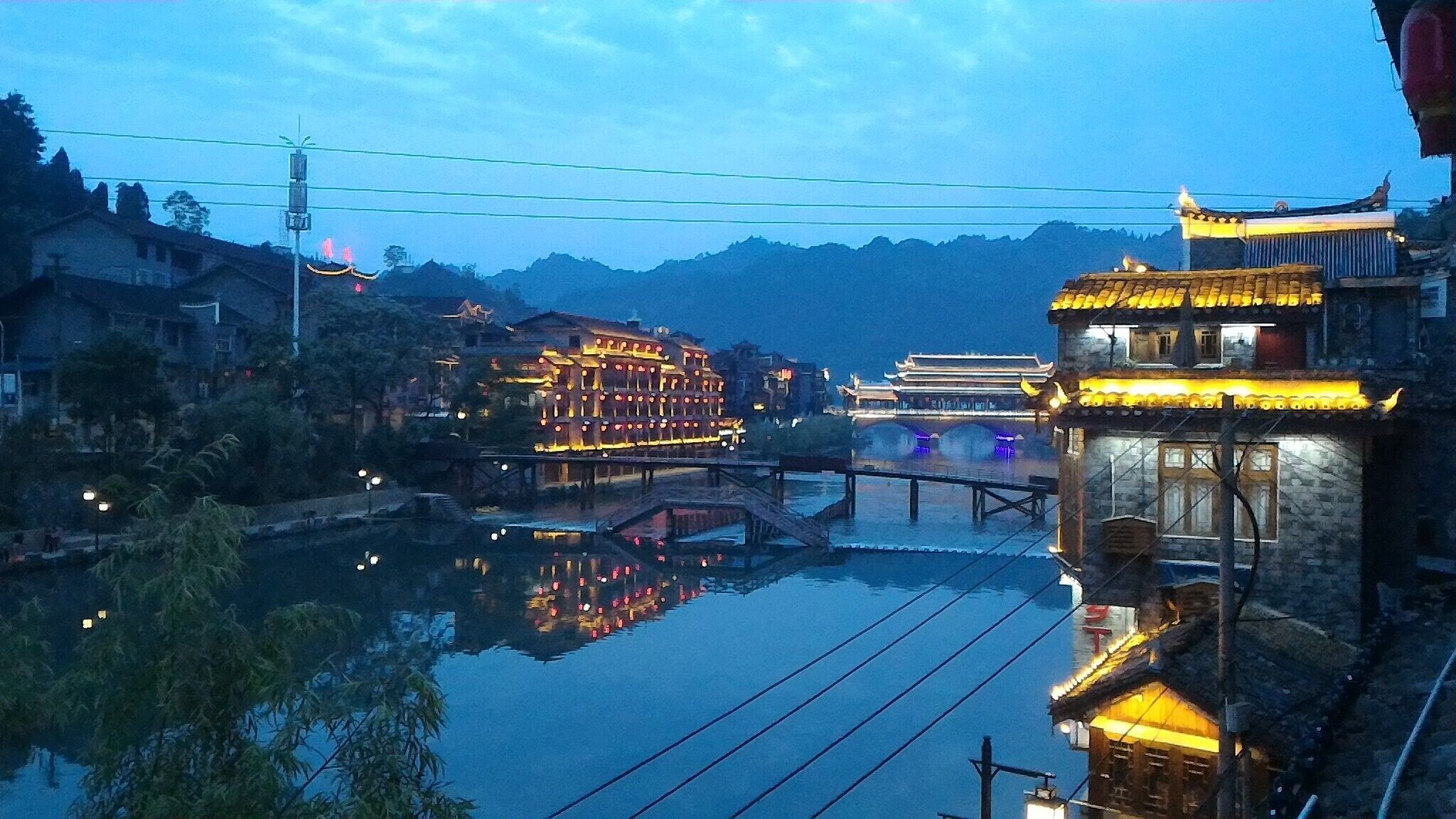 Un pintoresco pueblo acuático chino al atardecer, con edificios iluminados y su reflejo en el agua.