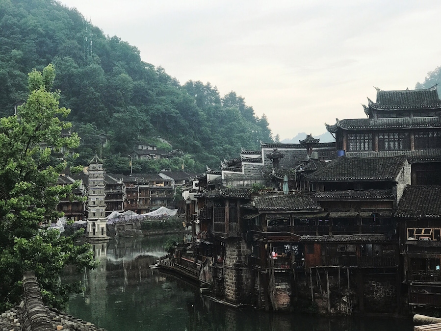 A traditional Chinese village with wooden buildings and a river.