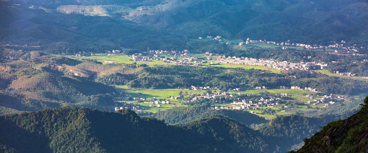 A valley with a small town surrounded by hills and forests.