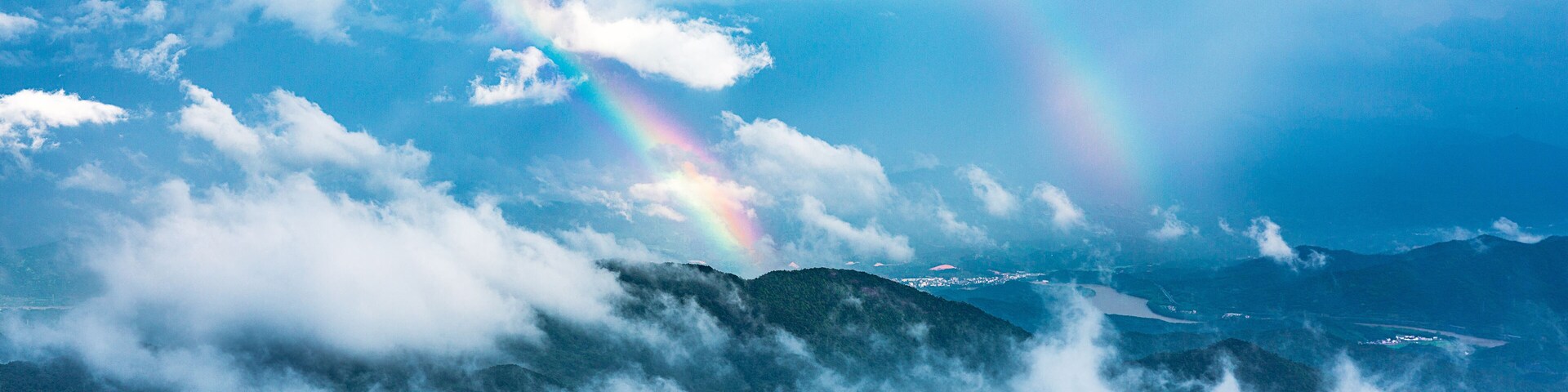 Un paisaje de montaña con un arcoíris y nubes.