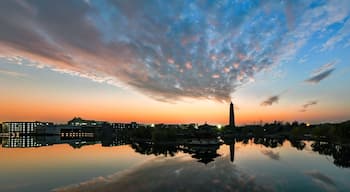 Un atardecer sobre un río tranquilo que refleja edificios y una pagoda.