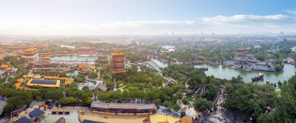 A traditional Chinese architectural complex with pagoda-style buildings, a river, and surrounding greenery.