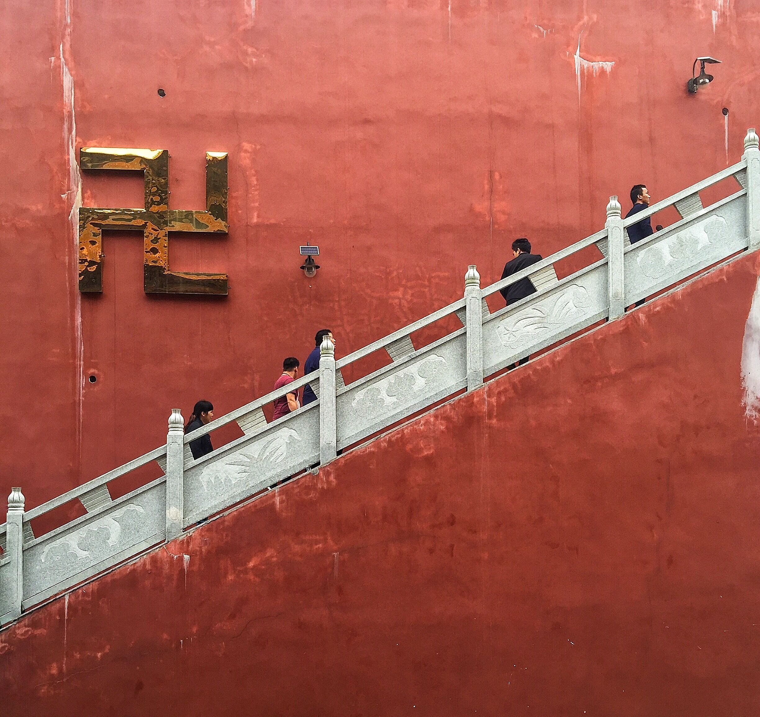 A red wall with a large gold Chinese character and a staircase.